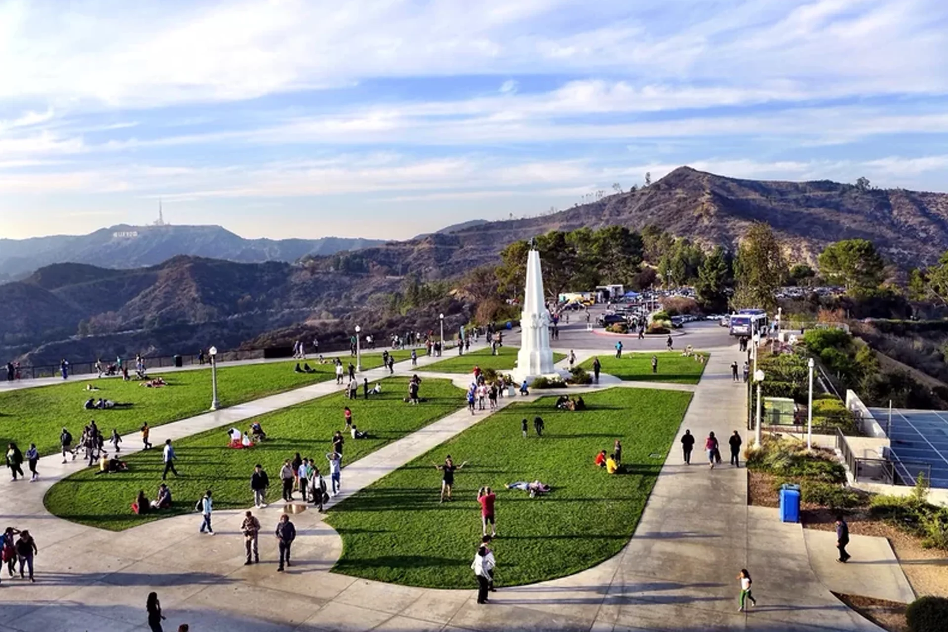 The iconic Hollywood Sign overlooking Griffith Park in Los Angeles, surrounded by green hills and a bright sky