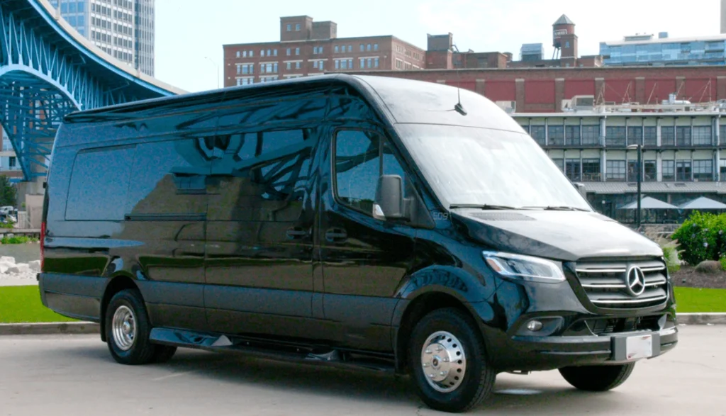 Black Mercedes Sprinter van parked near a bridge, representing an executive limo hire option for travelers