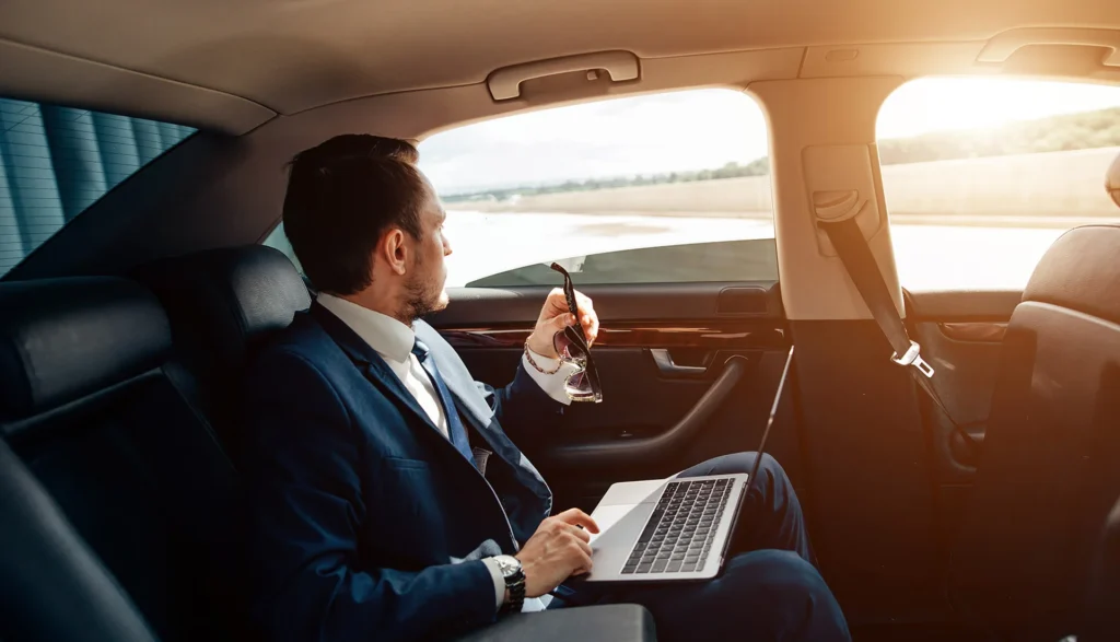 suited man relaxes in the back seat of a car emphasizing the safety and reliability of the limo service